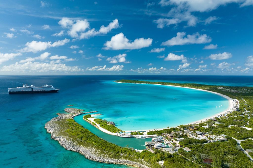 Aerial view of Half Moon Cay in the Bahamas, with its curved beach and a Holland America Line ship offshore