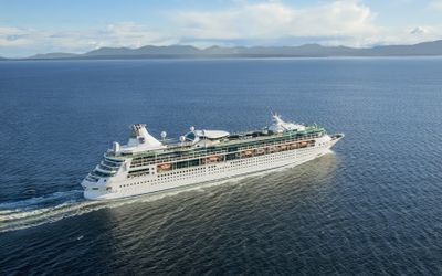 Rhapsody of the Seas sailing at sea, with mountains on the horizon